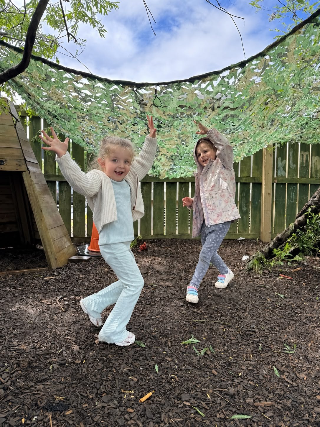 Two children dancing under the willow canopy